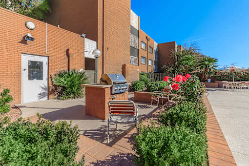 A brick building with a bench and a planter with red flowers.