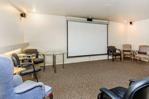 A conference room with a white screen and chairs.