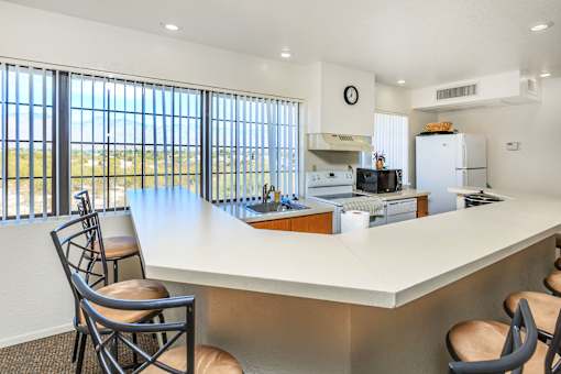 A kitchen with a large island and chairs.