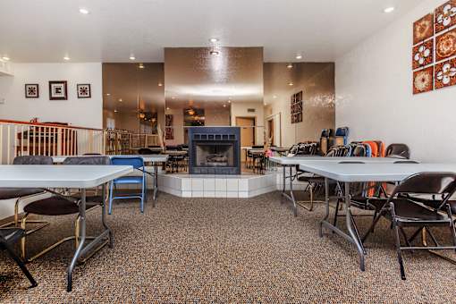 A room with a fireplace, chairs, and tables.