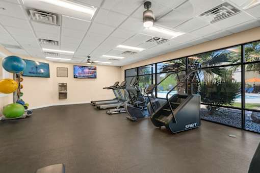 A gym with a treadmill and exercise balls.