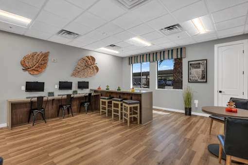 A room with wooden floors and a white ceiling with a row of desks and chairs.