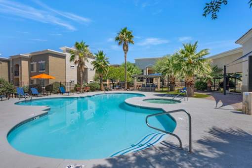 A swimming pool surrounded by palm trees and lounge chairs.