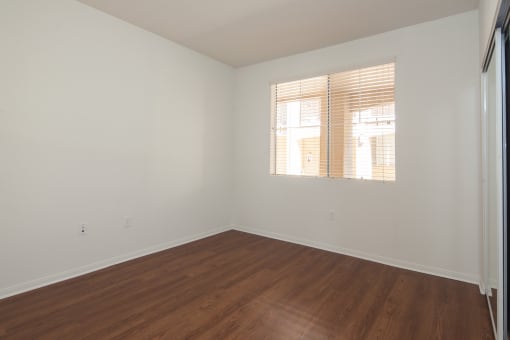 an empty room with wood floors and a window