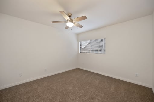 an empty room with carpet and a ceiling fan