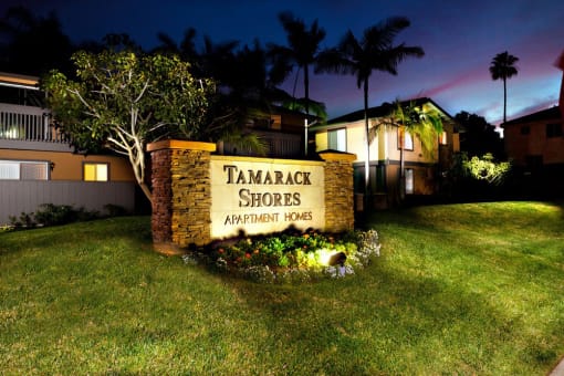 a sign for the tamarack shores apartments at night