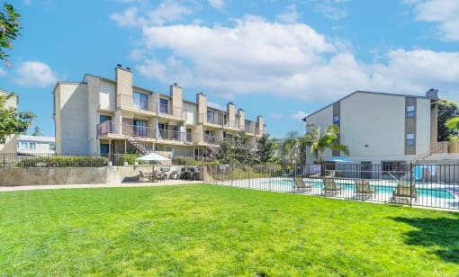 an apartment building with a lawn and a pool in front of it