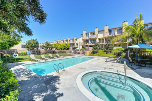 a swimming pool with a hot tub and a building in the background