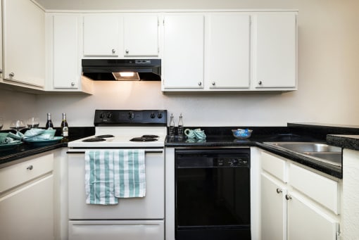 a kitchen with white cabinets and black countertops