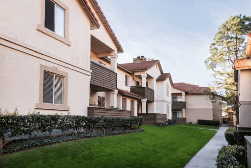 a row of apartment buildings with a green lawn in the foreground