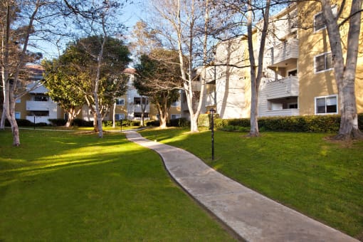 a path through the grass in front of apartment buildings