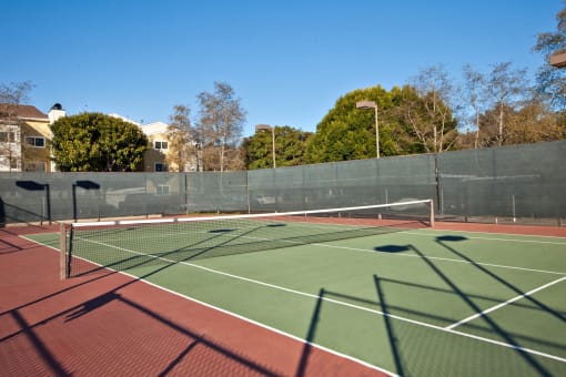 a tennis court with red and green court surfaces and a green fence