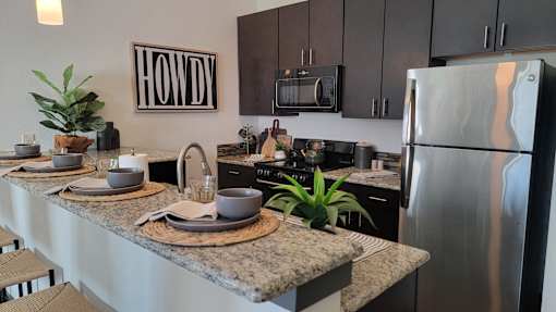 A modern kitchen with agranite countertop and stainless steel appliances at Urban Square, Denton, TX, 76210