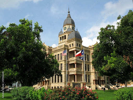 a large building with a clock tower and a flag on the front at Urban Square, Denton, TX