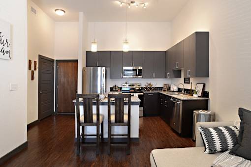 a view of a kitchen and a living room with a table and chairs at Epic Apartments, Denton, Texas