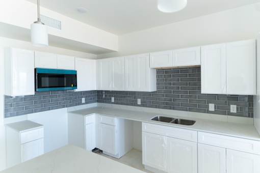 A kitchen with white cabinets and a blue backsplash.