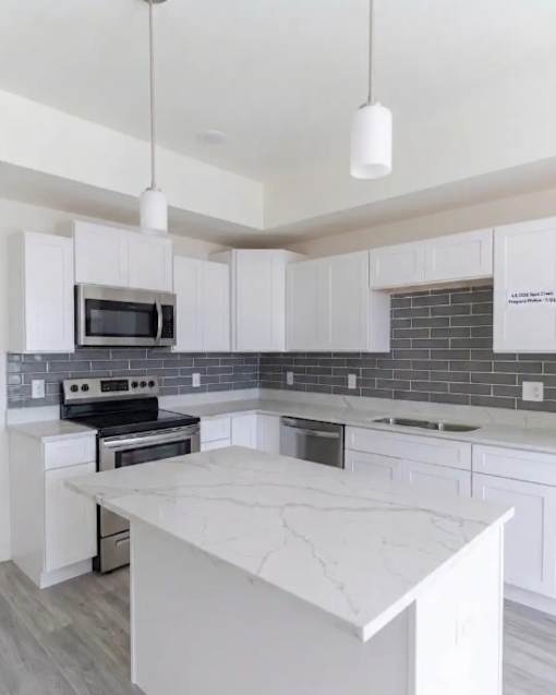 A kitchen with white cabinets and a marble countertop at Rock Creek Apartments, Gainesville, TX, 76240
