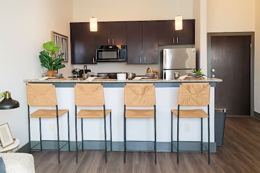 A kitchen with black cabinets and a blue island.