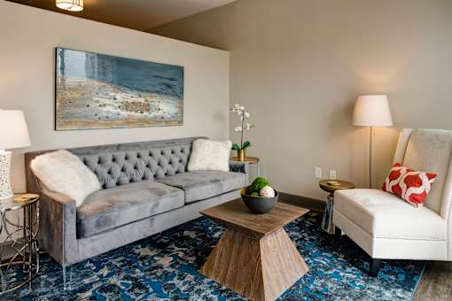 A grey couch with a tufted back sits in a living room with a painting on the wall above it. at 985 High Apartments, Ohio