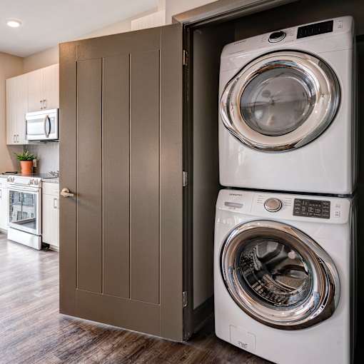 A white washing machine is in a cabinet in a modern kitchen. at 985 High Apartments, Ohio, 43201