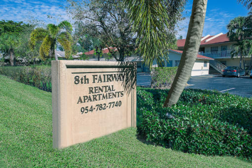 a sign for 8th fairway rental apartments in front of a palm tree
