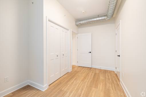 a bedroom with white walls and wood flooring and two closets
