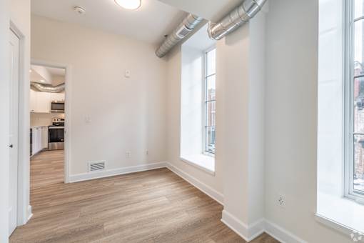 a living room with white walls and wood floors and a large window