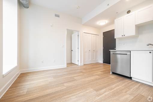 a renovated kitchen and living room with white cabinets and a stainless steel refrigerator