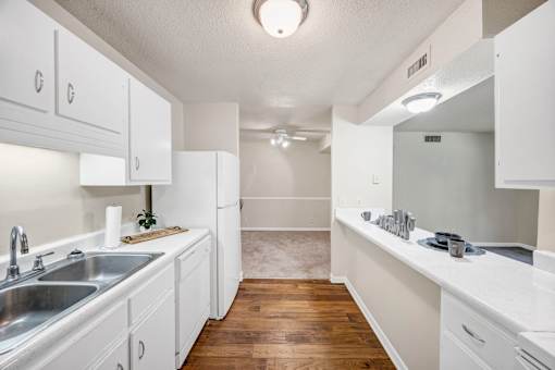 A kitchen with white cabinets and a wooden floor.