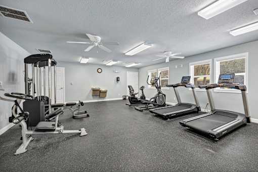 A spacious gym with treadmills, elliptical machines, and a weight bench.