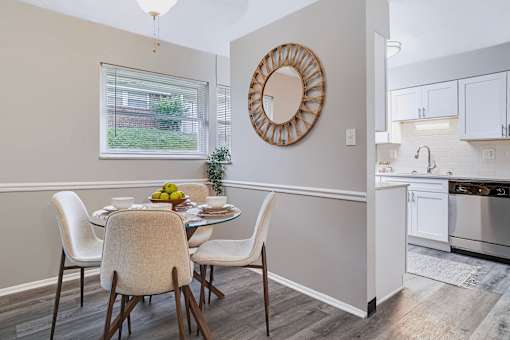 A dining room with a round mirror and a table set for two.