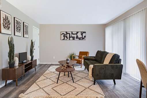 A living room with a couch, chair, and potted plants.
