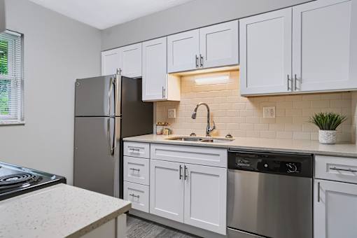 A kitchen with white cabinets and a black refrigerator.
