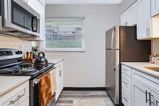A kitchen with a stove, microwave, and refrigerator.