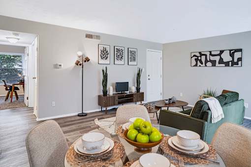 A dining room with a table set for two and a bowl of apples in the center.