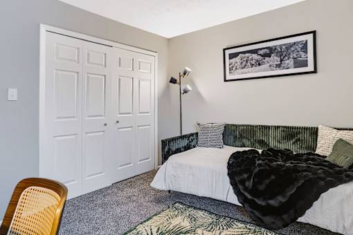 A bedroom with a bed, a chair, and a painting on the wall.