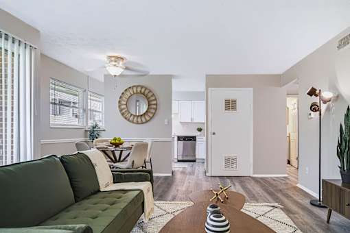 A living room with a green couch and a round mirror on the wall.