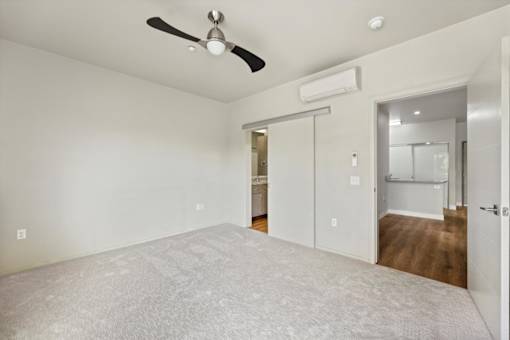 A room with a ceiling fan and sliding glass doors.