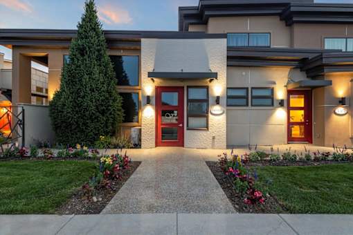 A modern house with a red door and a well-maintained garden. at Verraso Village Apartments, Meridian, ID