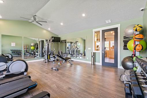 A gym with a variety of equipment including treadmills, weights, and exercise balls.