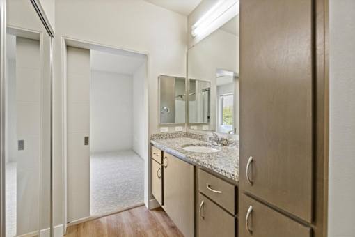 A bathroom with a sink, mirror, and wooden cabinets.