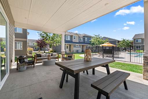 A patio with a table and benches under a white roof.
