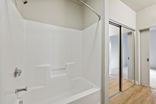 A white bathroom with a walk-in shower and a wooden floor.