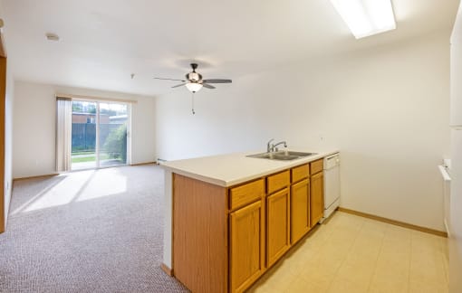 an empty kitchen with a sink and a ceiling fan