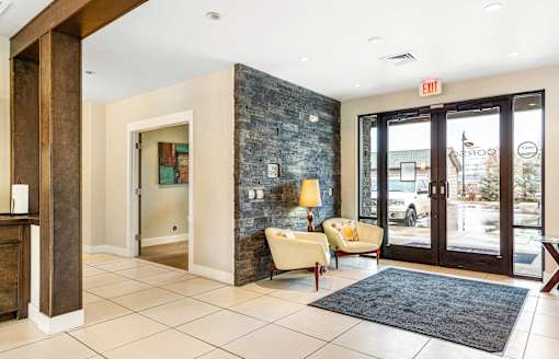 the lobby of a hotel with two chairs and a rug at Corso Apartments, Missoula, MT