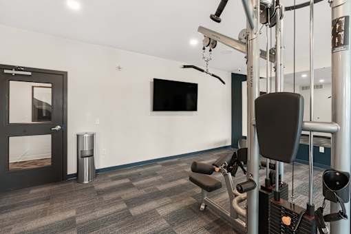 A gym with a television and a row of exercise machines at The Beaumont Apartments, Montana