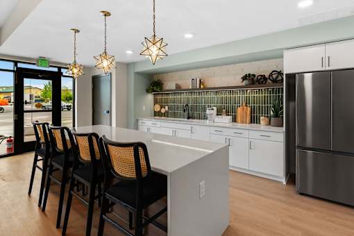 A kitchen with a white counter and black chairs at The Beaumont Apartments, Montana
