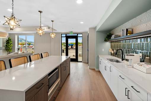 A modern kitchen with a long white counter and wooden floors at The Beaumont Apartments, MT 59715