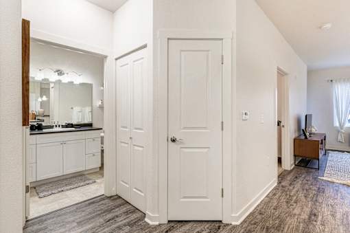 a bedroom with white doors and a bathroom with a sink and a mirror at Corso Apartments, Missoula, MT