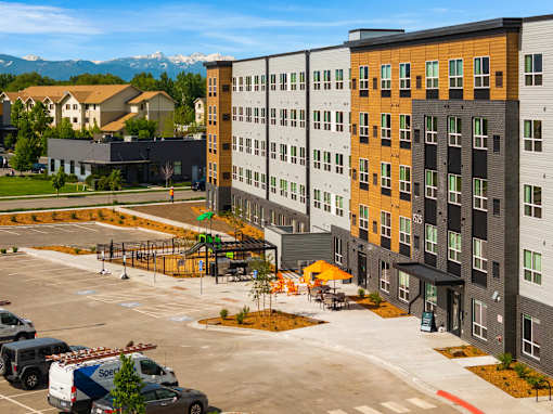 A parking lot with a building in the background at The Beaumont Apartments, Montana, 59715
